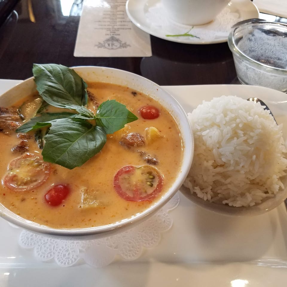 Red curry with tomatoes and basil, served with a side of white rice.