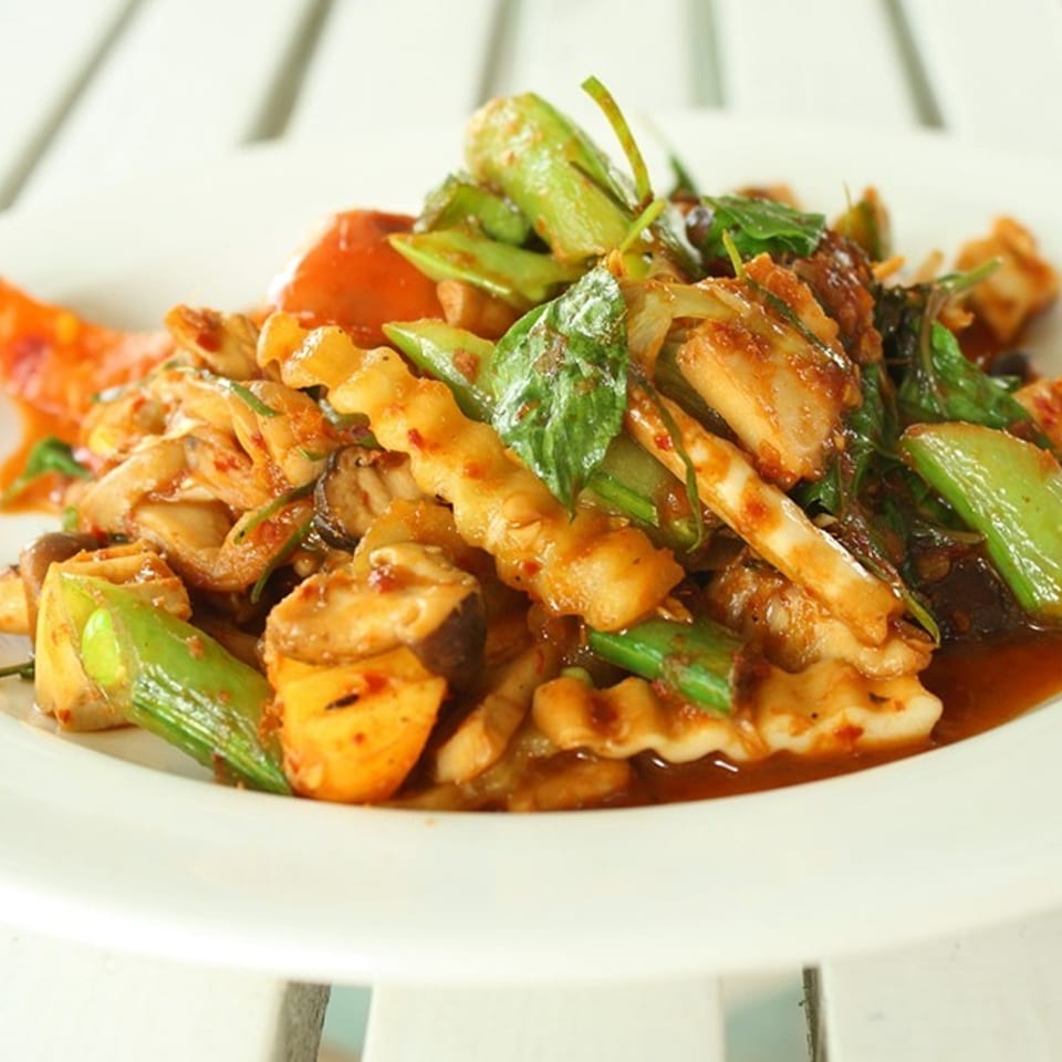 Spicy stir-fried squid with green beans, mushrooms, and basil in a rich red sauce.