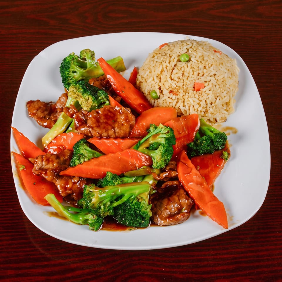 Beef and broccoli stir-fry with carrots and a side of fried rice on a white plate.