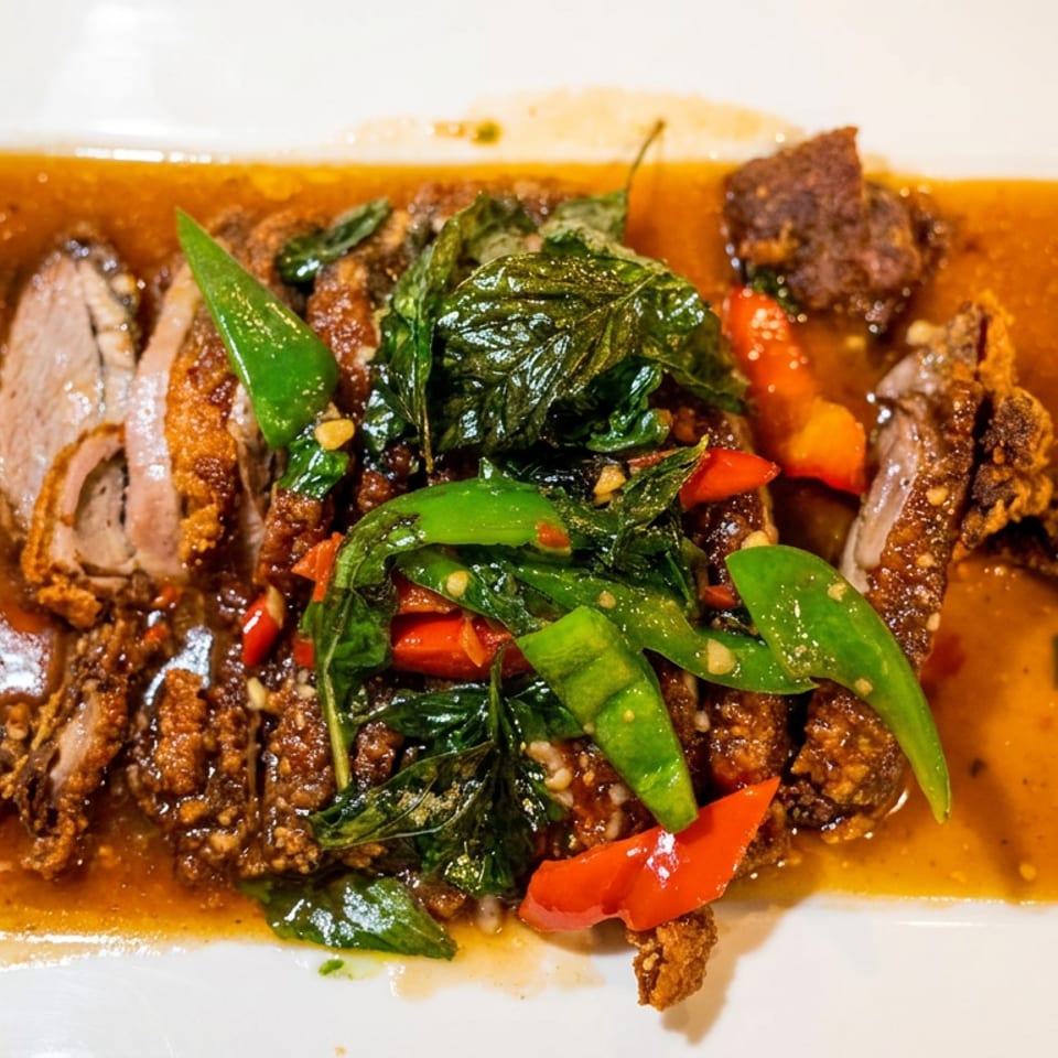 Crispy duck in a rich brown sauce, garnished with green basil, red and green peppers.
